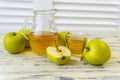 Green apples and jug with glass with apple juice on wooden background Royalty Free Stock Photo