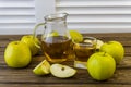 Green apples and jug with glass with apple juice on wooden background Royalty Free Stock Photo