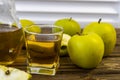 Green apples and jug with glass with apple juice on wooden background Royalty Free Stock Photo