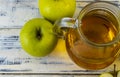 Green apples and jug with glass with apple juice on wooden background Royalty Free Stock Photo