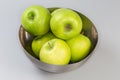 Green apples in metal bowl on a gray background