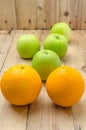 Green apples and orange on wooden panel