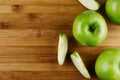 Green apples with slices on bamboo brown plank, top view, copy space.