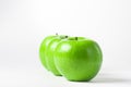 Green apples on a white background. Three green apples stand in a row, one apple after another