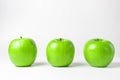 Green apples on a white background. Three green apples stand in a row, one apple after another