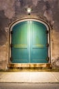 The green arched doors of a warehouse at night with a lone light Royalty Free Stock Photo