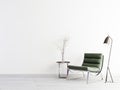 Green armchair and metal table on empty wall in simple living room interior.