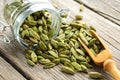 Green aromatic cardamom pods. Jar of whole cardamom pods and wooden scoop on table Royalty Free Stock Photo