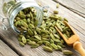 Green aromatic cardamom pods. Jar of whole cardamom pods and wooden scoop on table