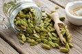 Green aromatic cardamom pods. Jar of whole cardamom pods and mortar of crushed seeds on table