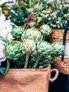 Green artichokes and flowers in small florist shop