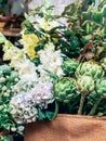 Green artichokes and flowers in small florist shop