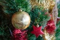 Green artificial Christmas tree decorated with beautiful golden ball, red and gold garlands, and other toys Royalty Free Stock Photo