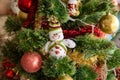 Green artificial Christmas tree decorated with beautiful smiling textile snowman, red and golden garlands and other toys Royalty Free Stock Photo