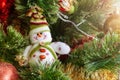 Green artificial Christmas tree decorated with beautiful smiling textile snowman, red and golden garlands, and other toys Royalty Free Stock Photo