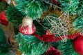 Green artificial Christmas tree decorated with star in a golden frame and interlacing threads; red bell with gold glitter