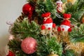 Green artificial Christmas tree decorated with two beautiful snowmen on sticks with red noses and hats, red balls, golden garlands Royalty Free Stock Photo