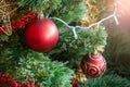 Green artificial Christmas tree decorated with two red balls: matte and glitter; and yellow and red garlands Royalty Free Stock Photo
