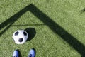 Green artificial turf soccer field with shadow from football goal net and soccer ball on sunny day outdoors. Football Royalty Free Stock Photo