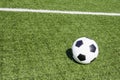 Green artificial turf soccer field with white line, shadow from football goal net and soccer ball on sunny day outdoors Royalty Free Stock Photo