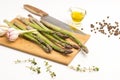 Green asparagus, garlic and a kitchen knife on a cutting board. Thyme sprigs, olive oil on table Royalty Free Stock Photo