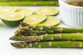 Green asparagus, sliced lemon, olive oil close up on marble serving board
