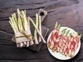 Green asparagus sprouts wrapped in ham on wooden table. Top view