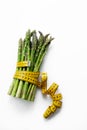 Green asparagus with tape measure on white in concept of health and diet, eating vegetables, losing weight and obesity Royalty Free Stock Photo