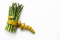 Green asparagus with tape measure on white in concept of health and diet, eating vegetables, losing weight and obesity. Copy space Royalty Free Stock Photo