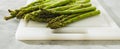 Green asparagus on a white cutting board close-up on the kitchen table