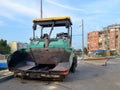 Green asphalt spreader machine at the site of road construction in the city