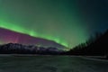 Green Aurora Over Mountains And A Frozen Lake