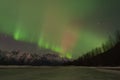 Green Aurora Over Mountains And A Frozen Lake