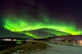 Green auroral light streaking through the sky in the middle of the night