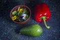 Green avocado, red pepper and fresh salad on rustic kitchen background