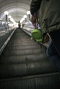 Green baby boots on mother`s hands climbing mechanical stairs