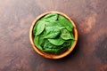 Green baby spinach leaves in wooden bowl on rustic stone table top view. Organic healthy food. Royalty Free Stock Photo