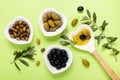 On the green background, bowls with extra virgin olive oil and variety of olives