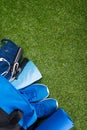 On the green background of the lawn, lies a blue sports bag with clothing and sports equipment for running and jumping high. Royalty Free Stock Photo