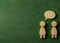 A green background sets the scene for two wooden figures facing each other, with a white speech bubble floating between Royalty Free Stock Photo