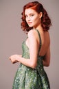 Green backless evening dress. Beautiful model wearing emerald high heels, modern feminine look