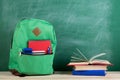 green backpack, calculator, books and notebooks on the background of the blackboard Royalty Free Stock Photo