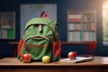 A green backpack in school classroom on the desk. School stationery, stationery, red apple, books, notebooks Royalty Free Stock Photo
