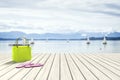 Green bag on a wooden jetty with sailing boats in the background