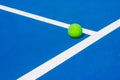 Green ball falling on floor nearly white lines of outdoor blue tennis hard court in public park. Royalty Free Stock Photo