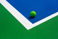 Green ball falling on floor nearly white lines of outdoor blue tennis hard court in public park. Royalty Free Stock Photo