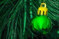 Green ball is on fir Christmas tree. Close up image of green New Year toy decoration on greenly background Royalty Free Stock Photo