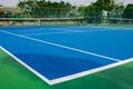 Green ball place on net pole and black net of outdoor blue tennis hard court in public park. Royalty Free Stock Photo