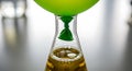A green balloon attached to the neck of an erlenmeyer flask containing a bubbling yellow liquid in a laboratory setting Background Royalty Free Stock Photo