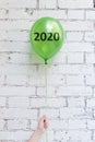 Green balloon with 2020 number in woman hand on white